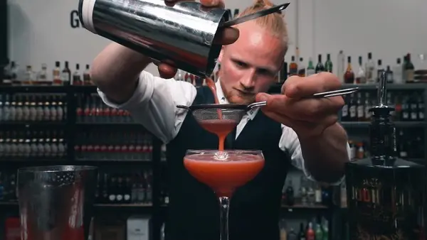 Bartender sier en friskblandet cocktail ned i glasset